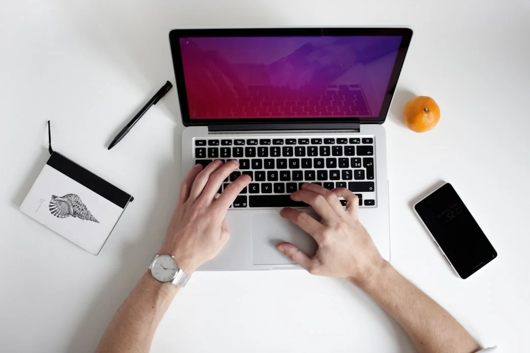 Un bureau lumineux avec un livre de design, un ordinateur portable et des outils créatifs, parfait pour stimuler l’inspiration.